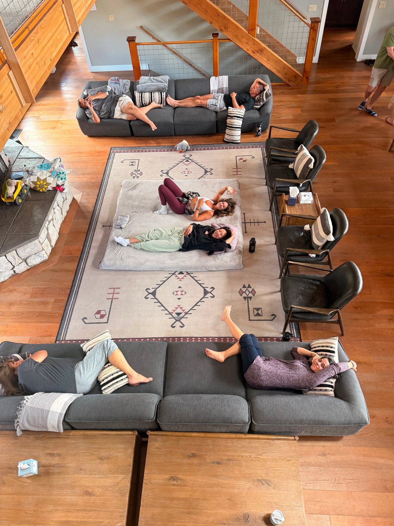 Guests resting on the great room's sofas and on a mat on the floor, seen from above
