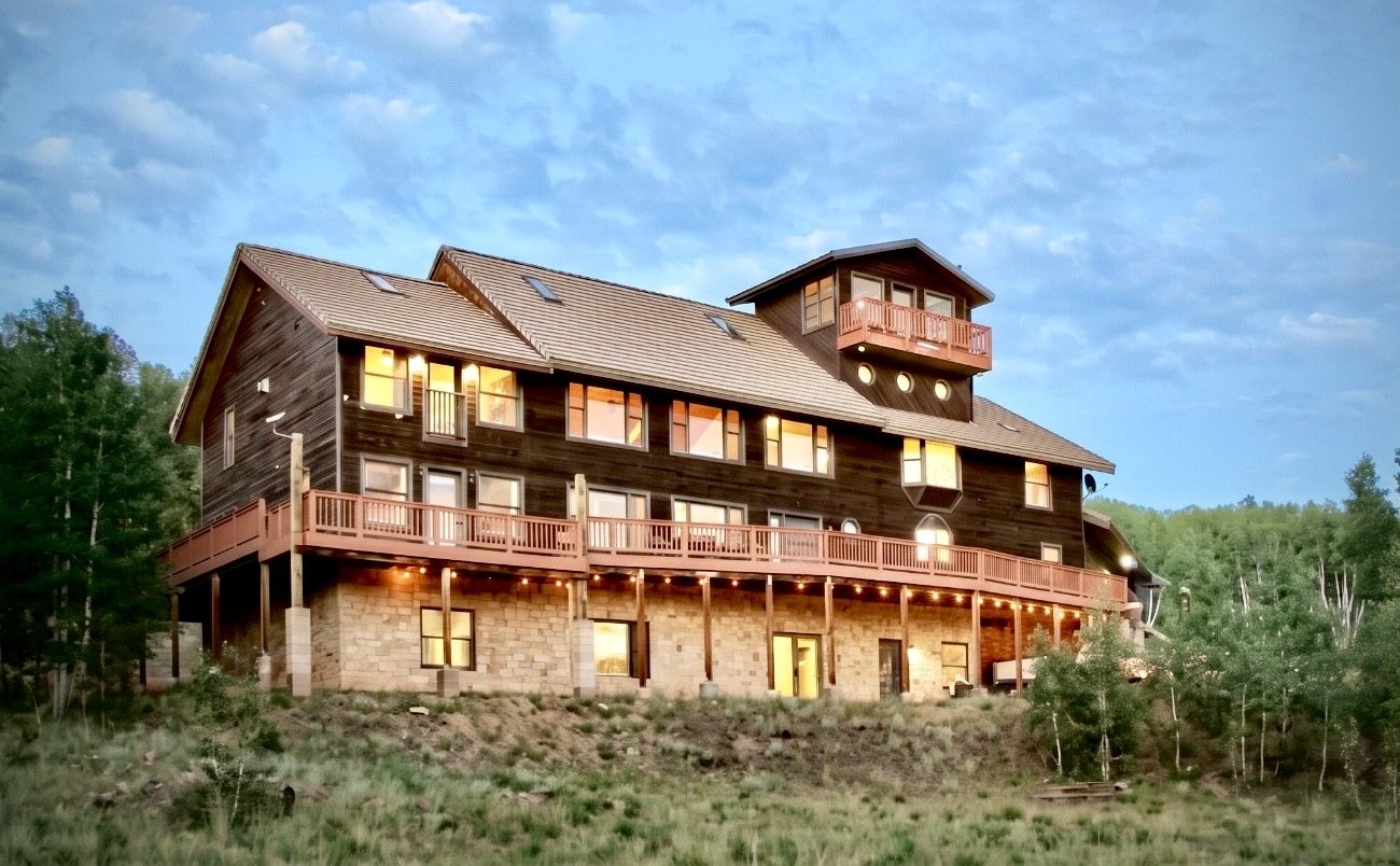 The retreat lodge at dusk, its windows lit, set among aspens